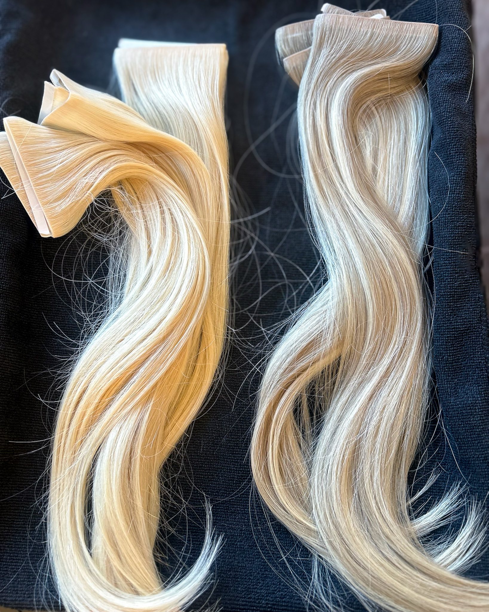 Two lengths of weft hair, one blonde and one dark, laid on black.